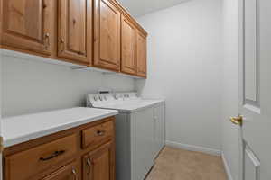 Laundry area featuring cabinets, independent washer and dryer, and light tile patterned floors