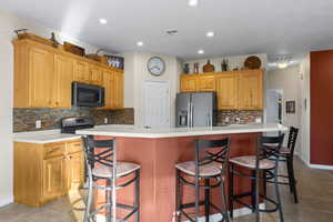 Kitchen featuring a butterfly island with sink, decorative backsplash, and appliances with stainless steel finishes