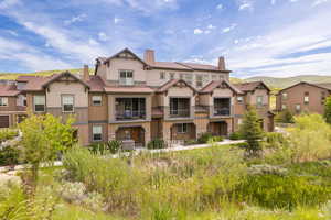 View of front of property featuring a balcony, a chimney, stone siding, and board and batten siding