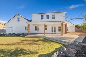 Rear view of house featuring french doors, a patio area, and a lawn