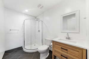 Bathroom featuring tiled shower, tile patterned flooring, vanity, and toilet