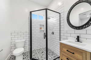 Bathroom featuring tile patterned floors, vanity, tile walls, toilet, and a shower with shower door