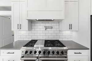 Kitchen featuring white cabinets, backsplash, and stainless steel appliances