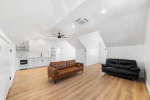 Living room with ceiling fan, light hardwood / wood-style floors, sink, and vaulted ceiling