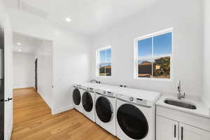 Clothes washing area featuring a wealth of natural light, sink, light hardwood / wood-style floors, and independent washer and dryer