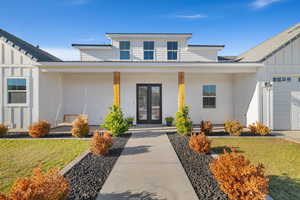 Property entrance with a lawn, a porch, and a garage