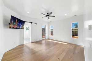 Spare room with light hardwood / wood-style floors, a barn door, and a healthy amount of sunlight