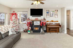 Living room featuring a wood stove, ceiling fan, and wood-type flooring