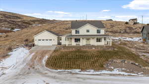 View of front of house featuring a mountain view, covered porch, an outdoor structure, and a garage