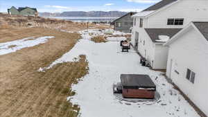 Snowy yard featuring a mountain view, a hot tub, and central air condition unit