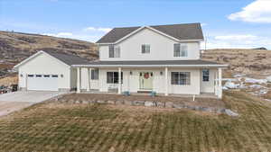 View of front of property featuring covered porch, a garage, and a front yard