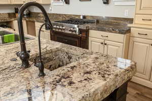 Kitchen featuring light stone countertops, wood-type flooring, and cream cabinetry