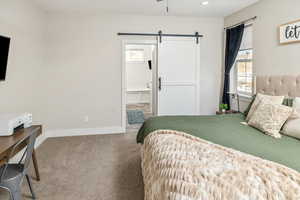 Bedroom featuring carpet flooring, a barn door, and connected bathroom