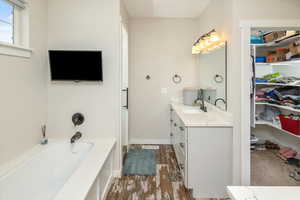 Bathroom featuring hardwood / wood-style flooring, vanity, and a tub