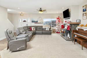 Living room with a wood stove, hardwood / wood-style floors, and ceiling fan with notable chandelier