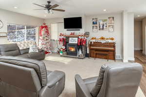 Living room with light hardwood / wood-style floors, a wood stove, and ceiling fan