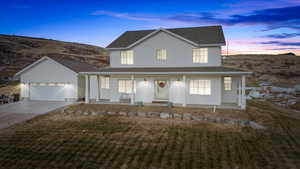 View of front of home with a porch, a garage, and a lawn