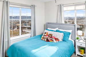 Carpeted bedroom with multiple windows and a mountain view