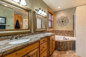 Bathroom featuring tile patterned flooring, vanity, and tiled tub