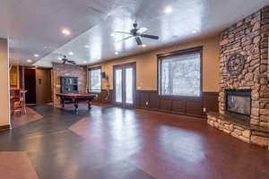 Game room with a stone fireplace, ceiling fan, a textured ceiling, and billiards