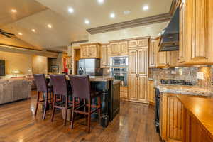 Kitchen with custom exhaust hood, lofted ceiling, an island with sink, dark hardwood / wood-style flooring, and stainless steel appliances