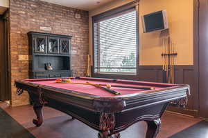 Recreation room with brick wall and pool table