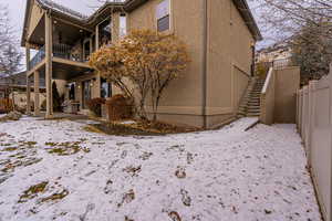 Snow covered back of property featuring a balcony and ceiling fan