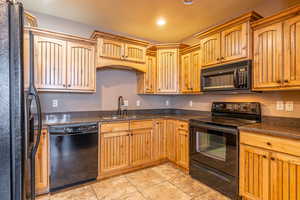 Kitchen featuring black appliances, light tile patterned flooring, and sink