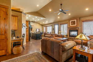 Living room featuring a multi sided fireplace, sink, vaulted ceiling, dark hardwood / wood-style floors, and ceiling fan