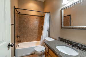 Full bathroom featuring tile patterned flooring, shower / bath combo, toilet, and vanity