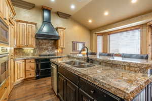 Kitchen with sink, dark hardwood / wood-style floors, an island with sink, vaulted ceiling, and custom range hood