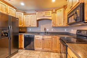 Kitchen with sink, light tile patterned flooring, and black appliances