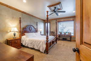 Carpeted bedroom with ceiling fan and crown molding