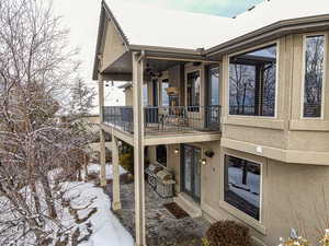 Snow covered rear of property with a balcony