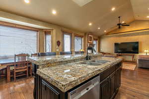 Kitchen featuring lofted ceiling, sink, stainless steel dishwasher, an island with sink, and dark hardwood / wood-style flooring