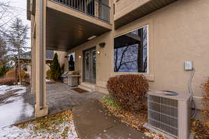 Snow covered property entrance featuring central AC, a balcony, a patio, and french doors