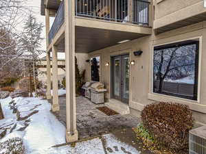 Snow covered patio featuring french doors and a balcony