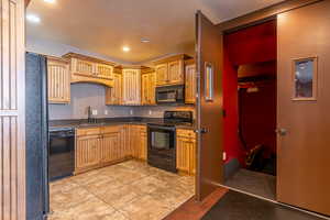 Kitchen with light tile patterned floors, sink, and black appliances