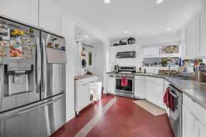 Kitchen featuring washer / dryer, white cabinetry, and appliances with stainless steel finishes