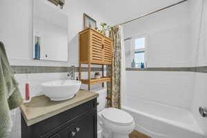 Full bathroom with shower / tub combo, vanity, tile walls, and toilet