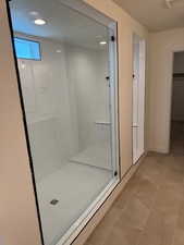 Bathroom with tile patterned floors and tiled shower