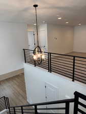 Staircase featuring a textured ceiling, hardwood / wood-style flooring, and an inviting chandelier