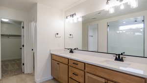 Bathroom featuring tile patterned flooring, vanity, and a shower