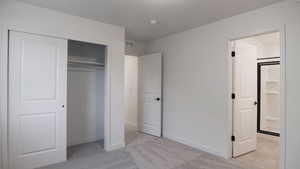 Unfurnished bedroom featuring light colored carpet and a closet