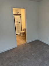 Unfurnished bedroom with ensuite bath and carpet floors