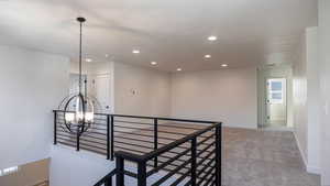 Hall featuring carpet flooring, a textured ceiling, and a notable chandelier