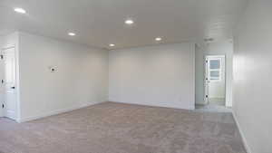 Unfurnished room with light carpet and a textured ceiling