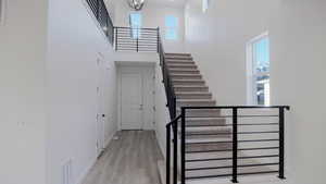 Stairway with hardwood / wood-style flooring and a towering ceiling