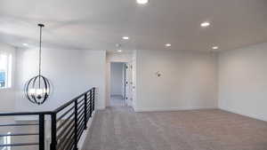 Unfurnished room with light carpet, a notable chandelier, and a textured ceiling