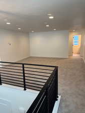 Hall featuring a textured ceiling and light carpet